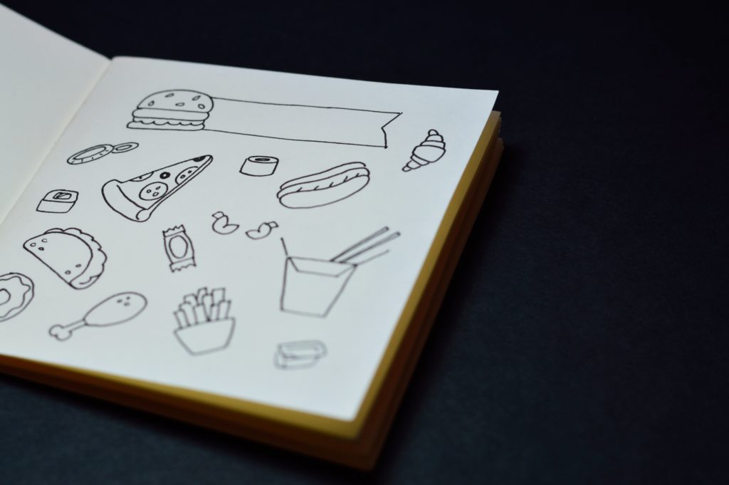 An open sketchbook full of drawings of food.